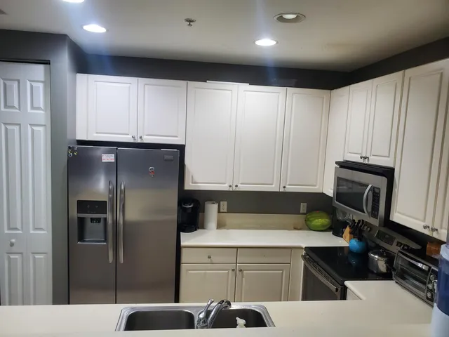 a kitchen with stainless steel appliances a refrigerator a sink a stove and white cabinets