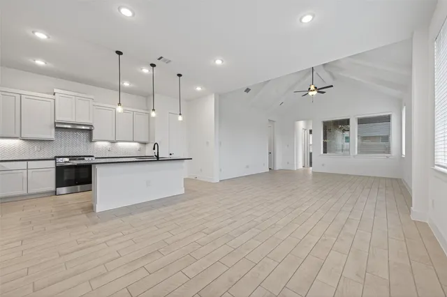 a view of kitchen with kitchen island white cabinets appliances and a window