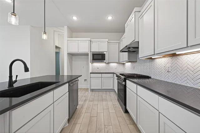 a kitchen with stainless steel appliances granite countertop a sink a stove and a refrigerator