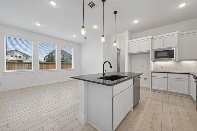 a kitchen with stainless steel appliances granite countertop a sink a stove and a wooden floors