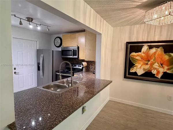 a kitchen with stainless steel appliances granite countertop a sink a stove and a refrigerator