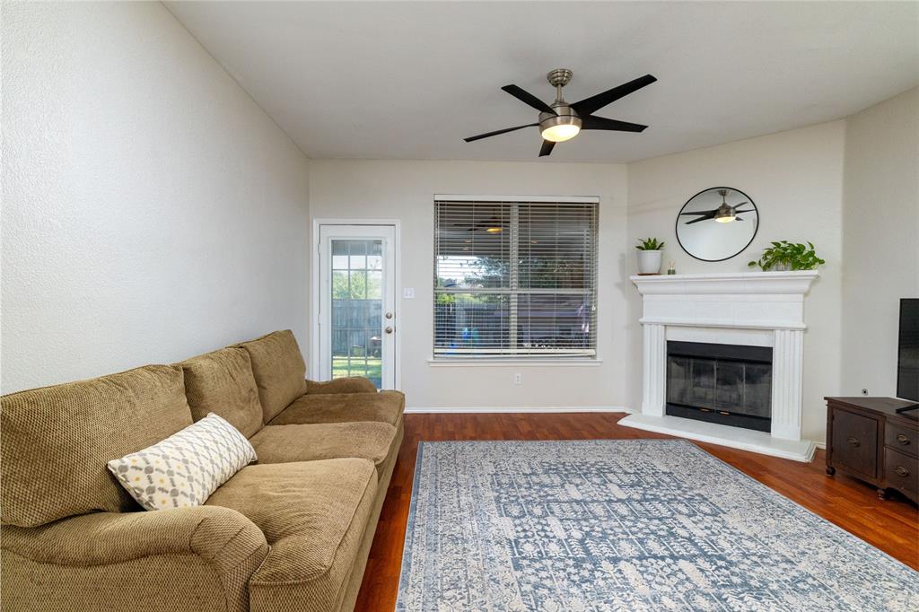 4025 Chisos Rim Trail Fort Worth, TX 76244 - Photo 10 of 40 Living area featuring wood-finish flooring, a white mantel fireplace, a ceiling fan with integrated lighting, and a glass-paneled door opening to the exterior