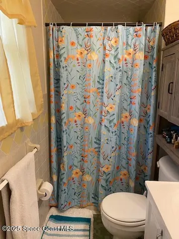 a white toilet sitting next to a shower curtain