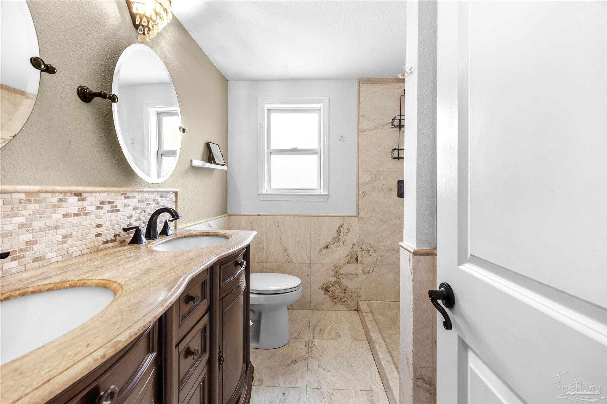 889 Dolphin Road Milton, FL 32583 - Photo 37 of 67 a bathroom with a granite countertop sink toilet and a mirror