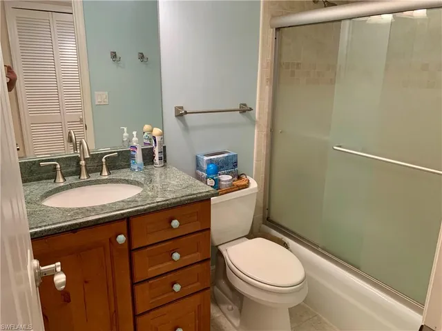 a bathroom with a granite countertop toilet sink and mirror