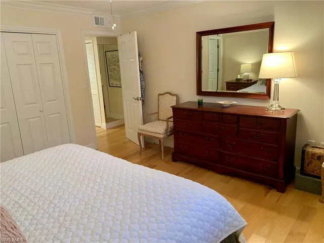 a bedroom with a bed and a lamp on dresser