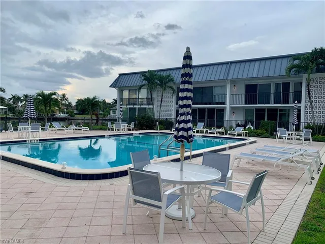 a view of a house with a swimming pool and a chairs and table in a patio