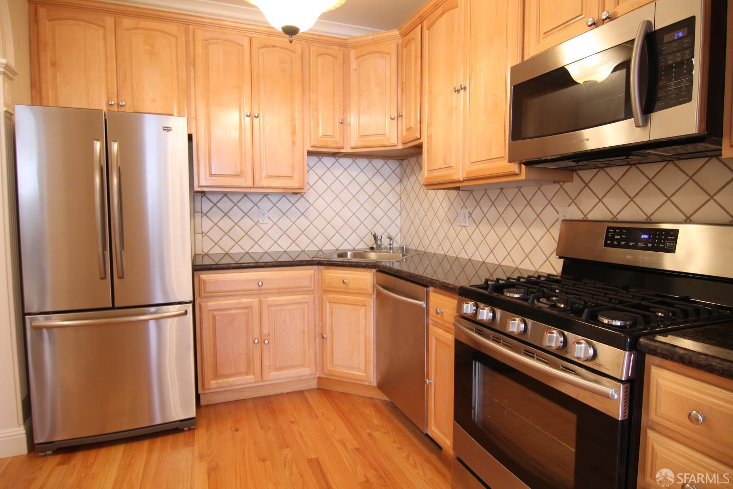 471 7th Avenue, Unit 2 San Francisco, CA 94118 - Photo 2 of 7 a kitchen with granite countertop a refrigerator stove and microwave