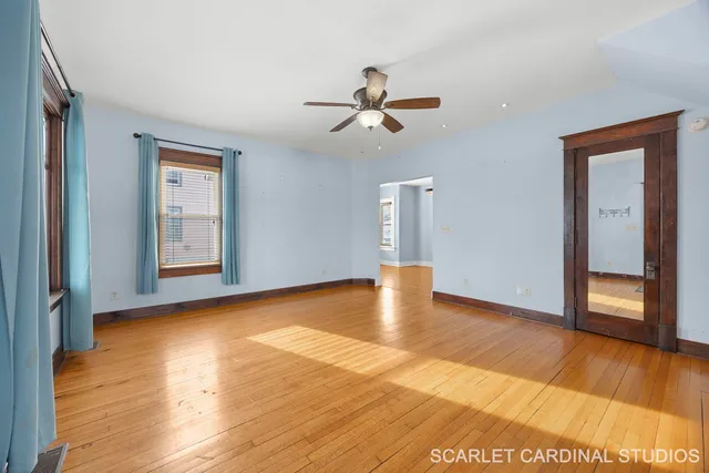 a view of an empty room with window and wooden floor