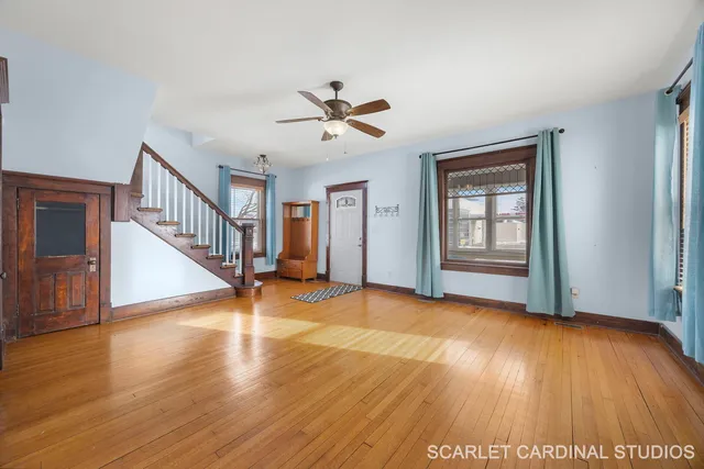 a view of an empty room with wooden floor and a ceiling fan