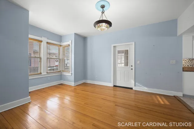 a view of an empty room with window and wooden floor