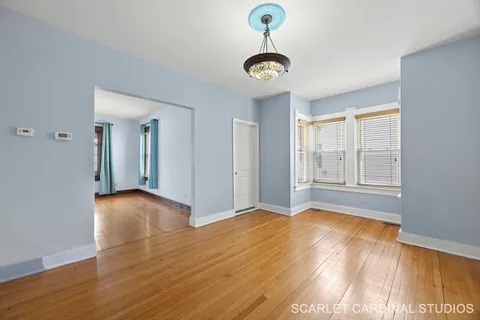 a view of an empty room with window and wooden floor