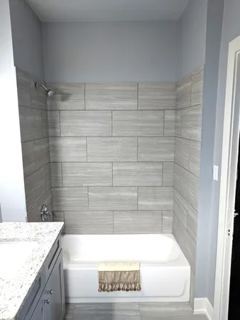 a bathroom with a granite countertop bathtub and shower