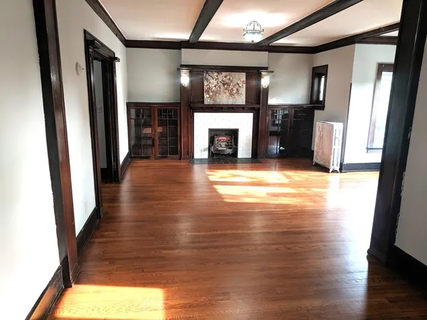 an empty room with wooden floor fireplace and windows