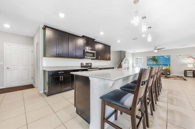 a kitchen with stainless steel appliances kitchen island granite countertop a table chairs and a refrigerator