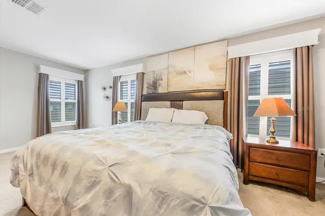 a large white bed in a bedroom next to a window