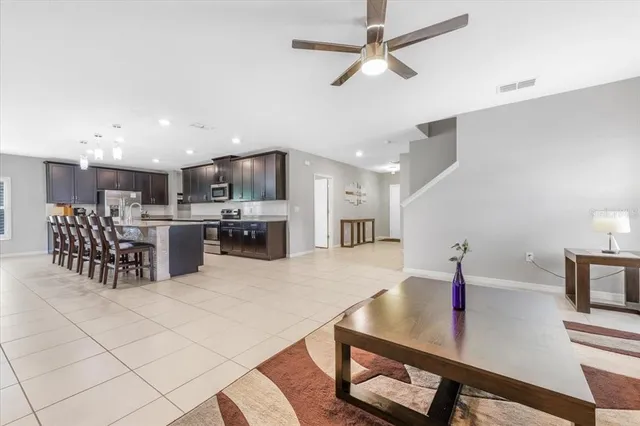 a kitchen with stainless steel appliances kitchen island granite countertop a sink a stove a microwave oven a refrigerator with island and chairs with wooden floor