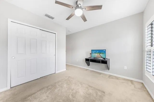 an empty room with ceiling fan and window