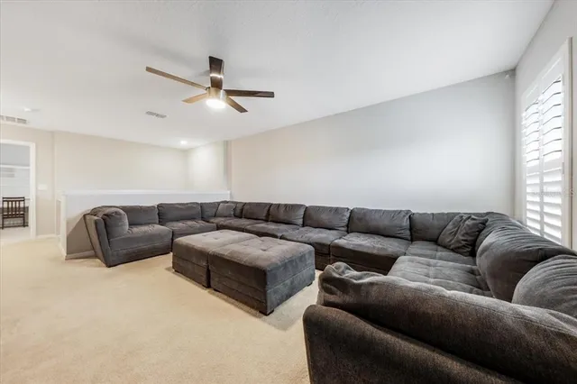 a living room with couches and a ceiling fan