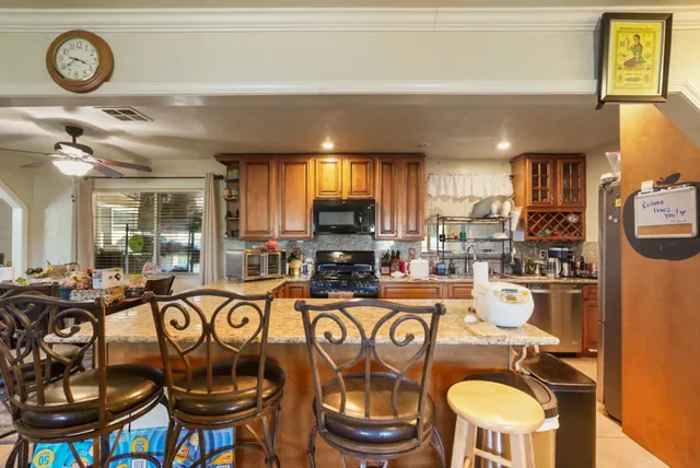 a kitchen with stainless steel appliances granite countertop a stove top oven a dining table and chairs with wooden floor