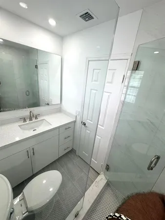 a spacious bathroom with a double vanity sink a toilet and a mirror