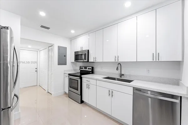 a kitchen with white cabinets sink and stainless steel appliances