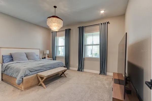 a spacious bedroom with a bed and a chandelier