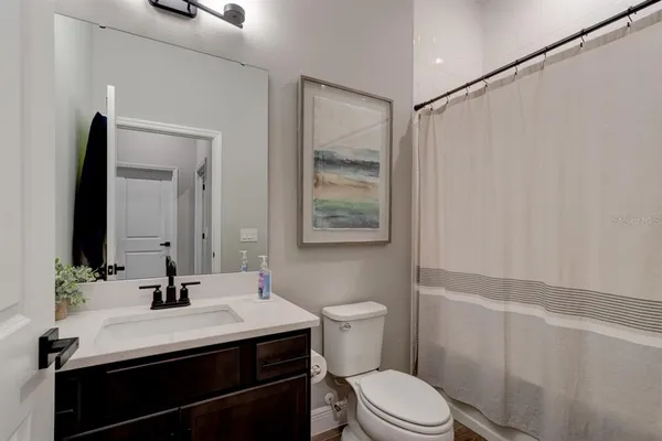 a bathroom with a sink a toilet a mirror and shower