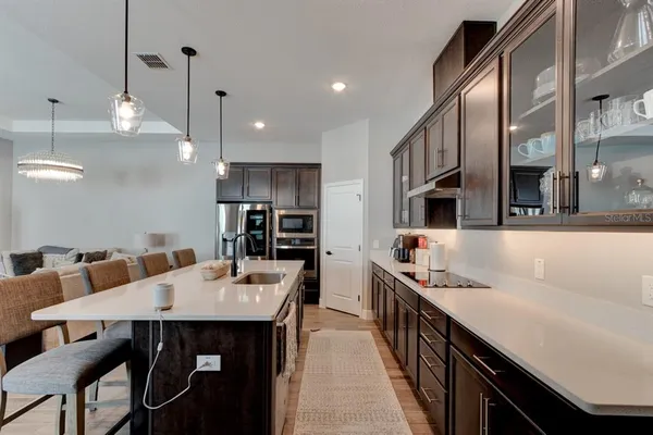 a kitchen with stainless steel appliances kitchen island granite countertop a table chairs in it and wooden floors