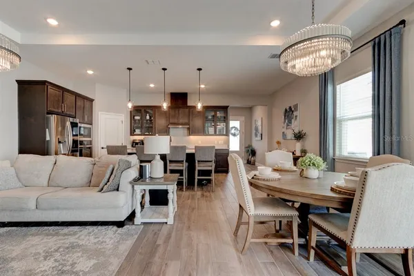 a living room with furniture a large window and a dining table with wooden floor