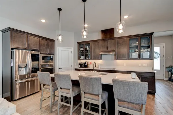 a kitchen with stainless steel appliances granite countertop a table chairs refrigerator and microwave