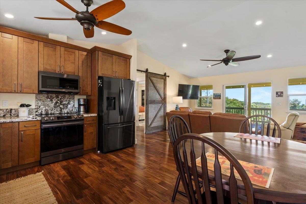 139 Pauwela Road Haiku, HI 96708 - Photo 5 of 42 a kitchen with stainless steel appliances granite countertop a refrigerator a stove a sink a dining table and chairs with wooden floor