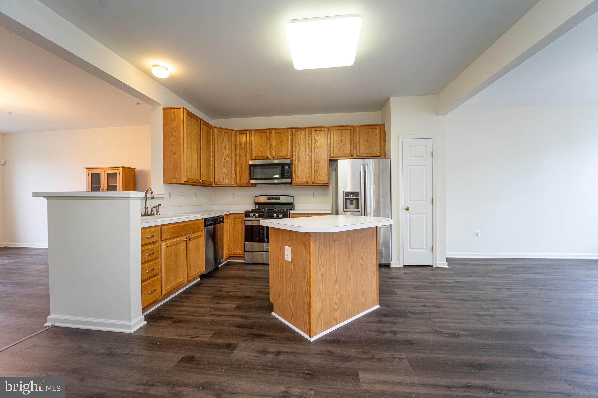 4309 Windflower Way Bowie, MD 20720 - Photo 12 of 46 a kitchen with wooden floors stainless steel appliances a window and a counter