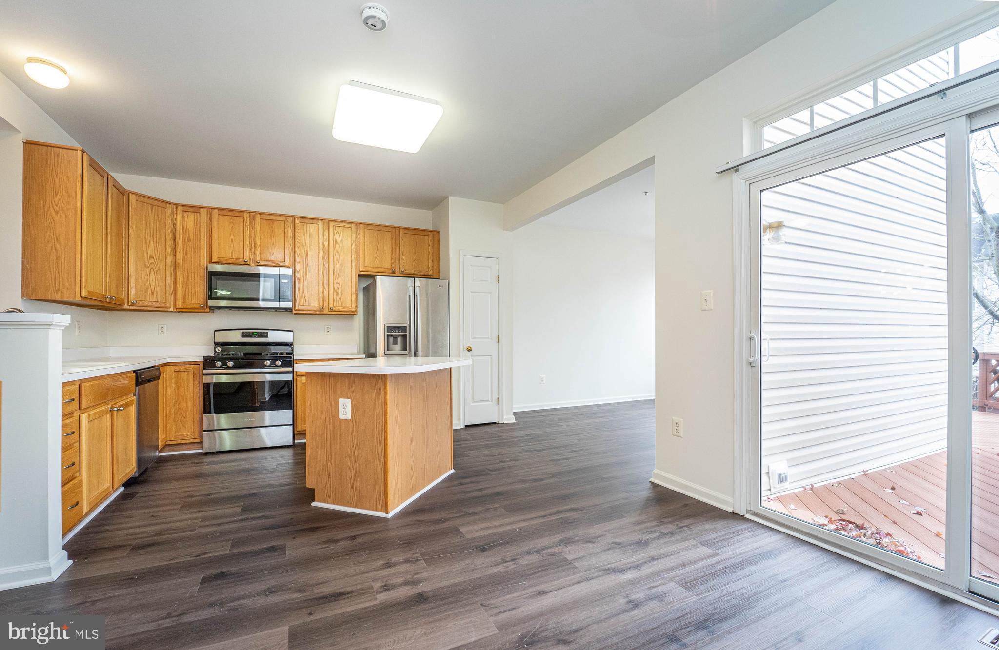 4309 Windflower Way Bowie, MD 20720 - Photo 36 of 46 a kitchen with wooden floors wooden cabinets and stainless steel appliances