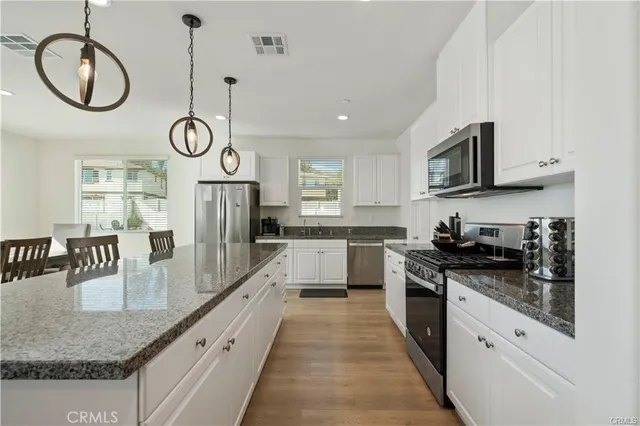 a kitchen with a table chairs a stove a microwave and cabinets