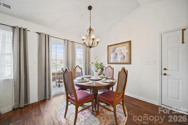 a view of a dining room and livingroom with furniture wooden floor a chandelier