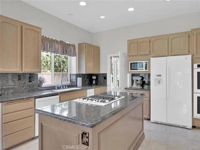 a kitchen with stainless steel appliances granite countertop a sink refrigerator and cabinets