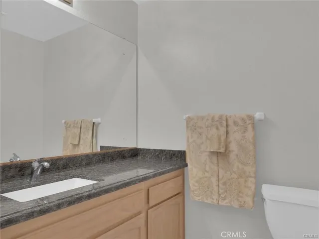 a bathroom with a granite countertop sink a toilet and a mirror