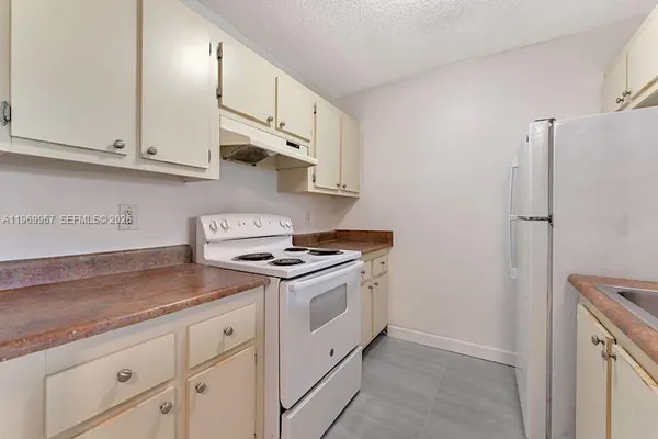 a kitchen with granite countertop white cabinets and white appliances