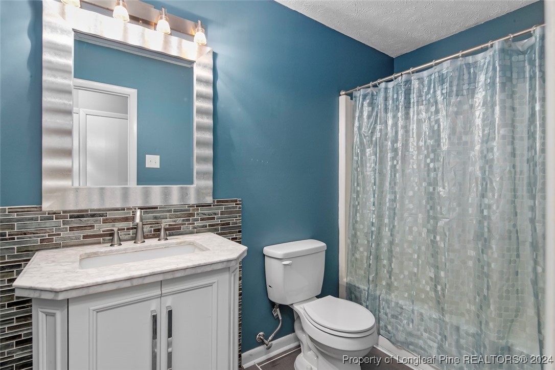 3009 Rouse Road Fayetteville, NC 28306 - Photo 24 of 37 a bathroom with a granite countertop sink a toilet and a mirror