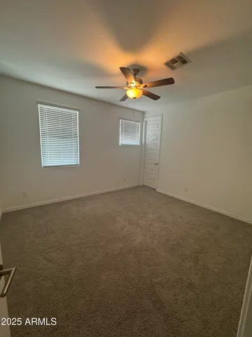 an empty room with a chandelier fan and windows