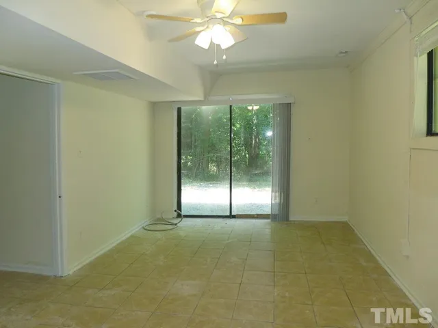 a view of an empty room with window and chandelier fan