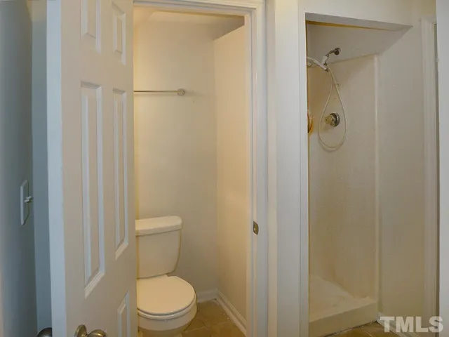a white toilet sitting next to a shower