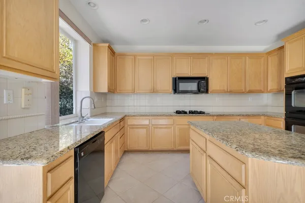 a kitchen with granite countertop a sink and a stove top oven with wooden floor