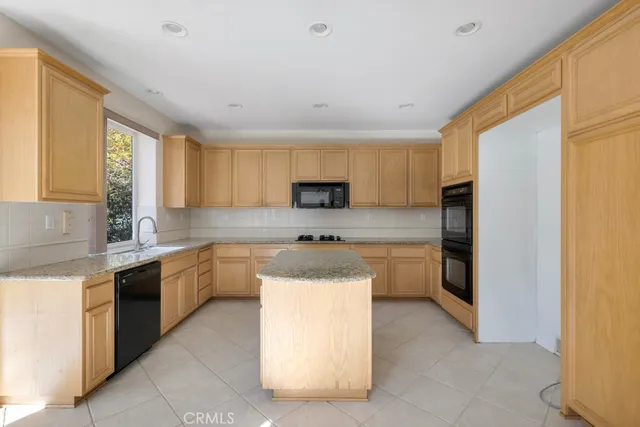 a kitchen with stainless steel appliances a sink a stove a refrigerator cabinets and a window