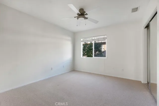 an empty room with a chandelier fan and windows