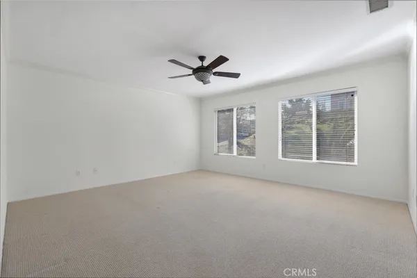 an empty room with windows and ceiling fan