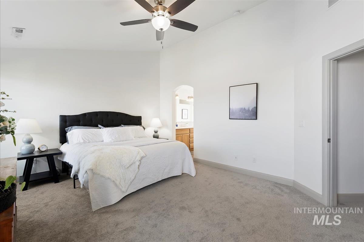 5932 West Quintale Drive Meridian, ID 83646 - Photo 24 of 40 Carpeted bedroom with high vaulted ceiling, a ceiling fan, arched walkways, and connected bathroom