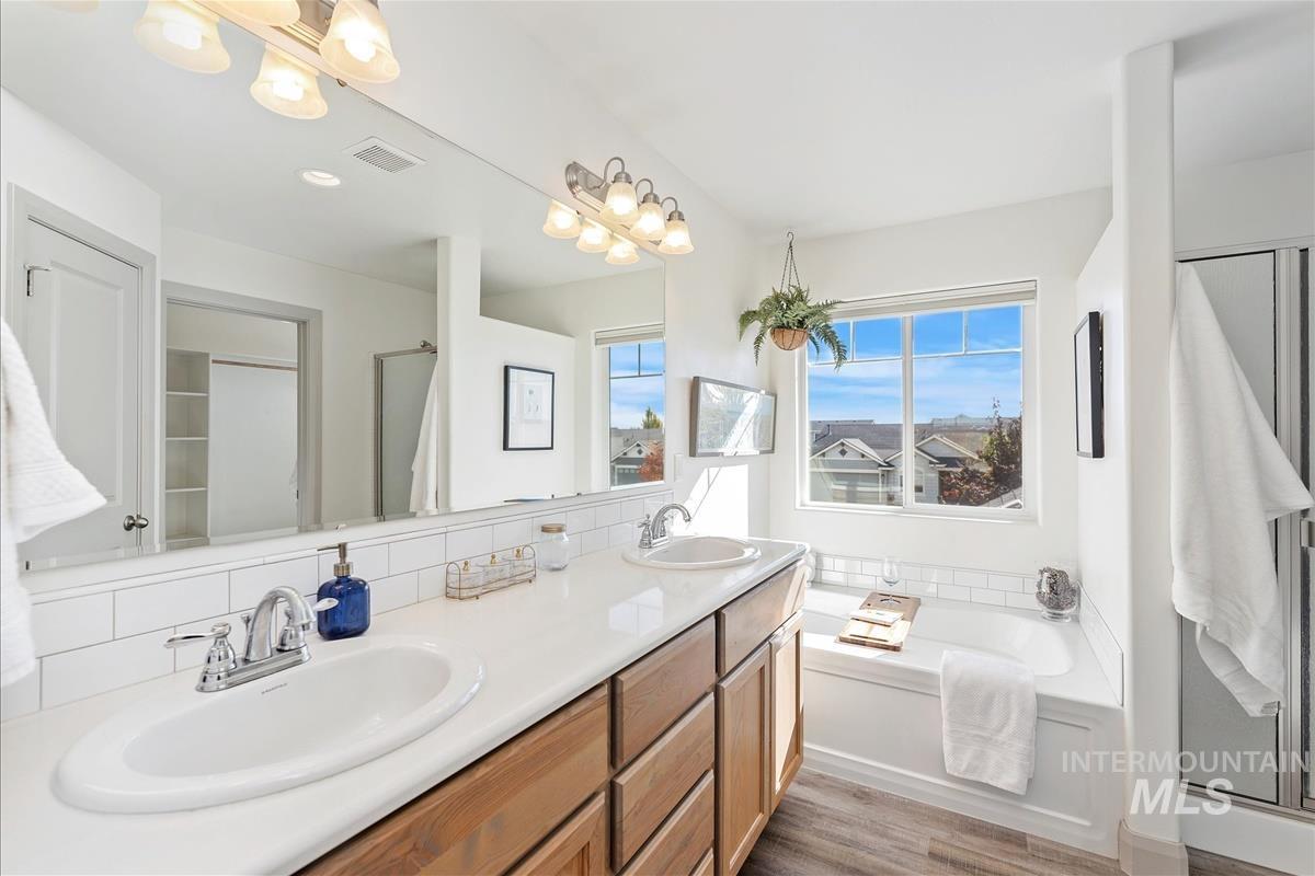 5932 West Quintale Drive Meridian, ID 83646 - Photo 25 of 40 Full bath featuring double vanity, a shower stall, a bath, and light wood-style flooring