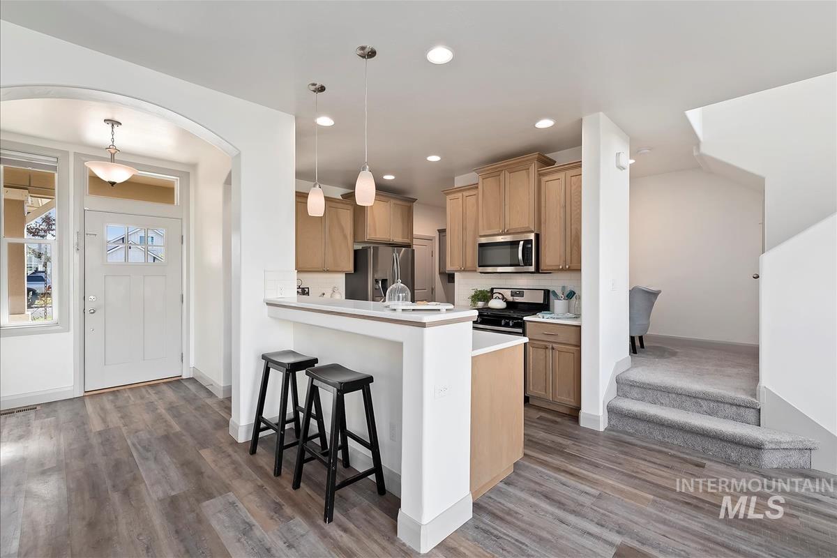 5932 West Quintale Drive Meridian, ID 83646 - Photo 10 of 40 Kitchen with light countertops, a breakfast bar, hanging light fixtures, stainless steel appliances, and a peninsula